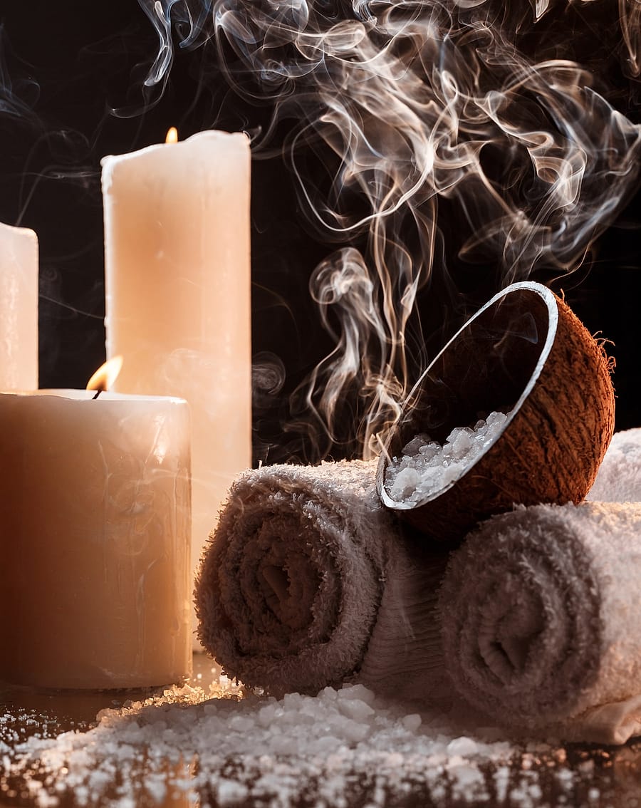 Candles, rolled towels and a coconut bowl of salt with curling steam